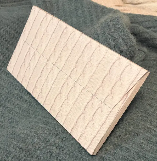 A couple fat envelopes of my design laid out against a green furry sweater.