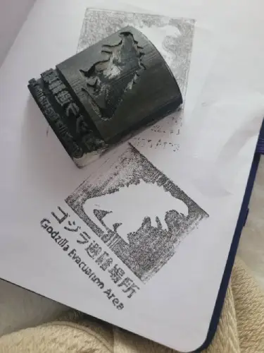 The 3D stamp next to the ink imprint it made of Godzilla.