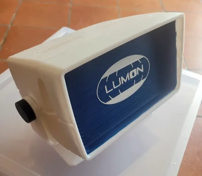 A small white retro computer console with a navy painted 'screen' and the Lumon logo from Severance on it.