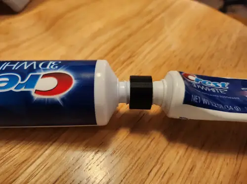 a small black 3D design holding two toothpaste tubes together by their nozzles.